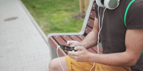 a man looking at his mobile phone while he waits at a bus stop