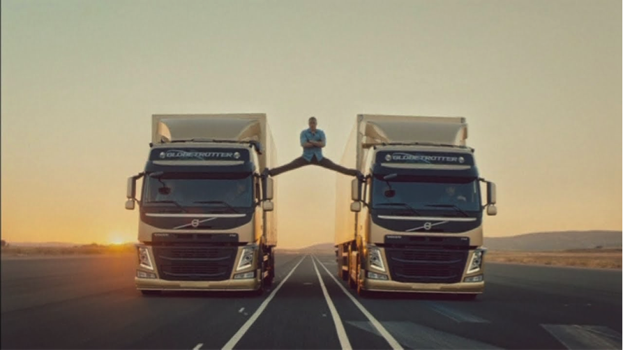 An actor standing in the air space between two trucks