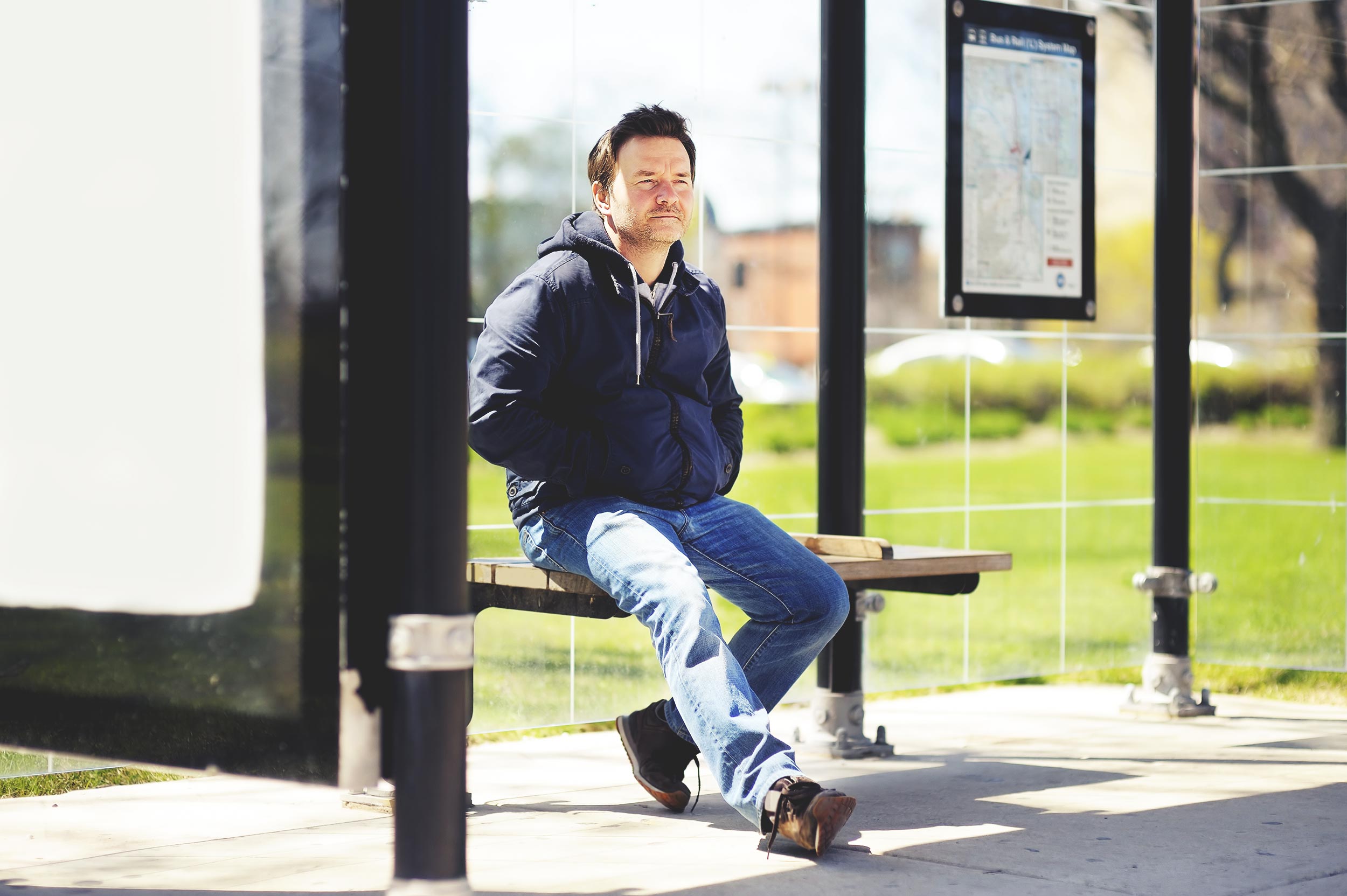 a man sitting at a bus stop awaiting a bus