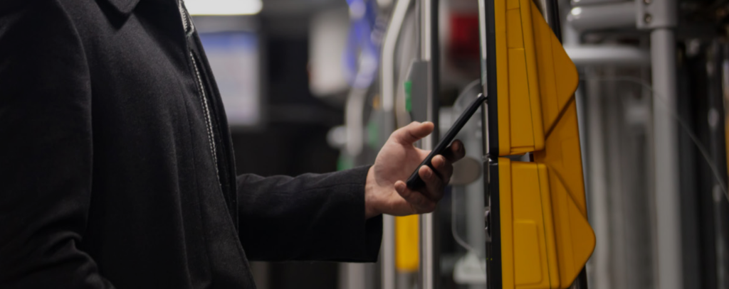 person swiping their phone to enter transit bus