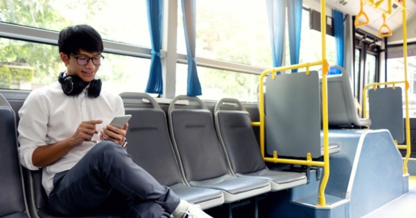young man on a public bus looking at his mobile phone