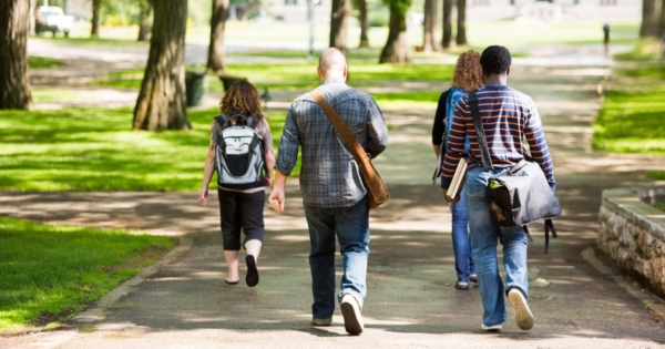 view of the backs of students walking on a college campus sidewalk
