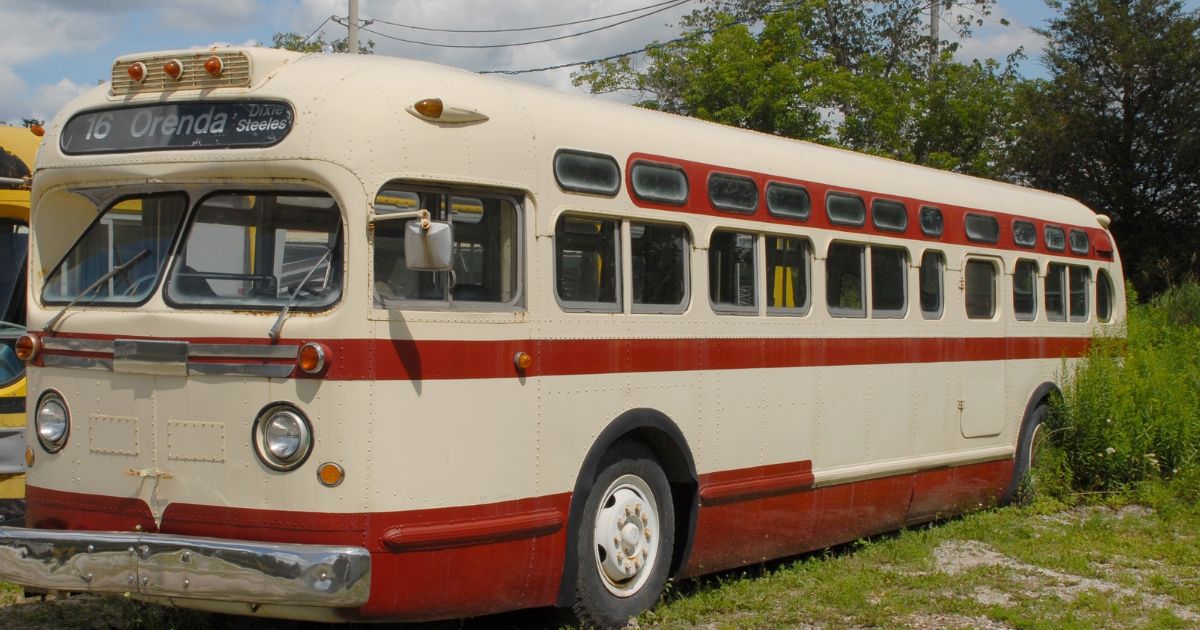 a vintage public transit bus parked outdoors in a rural parking lot