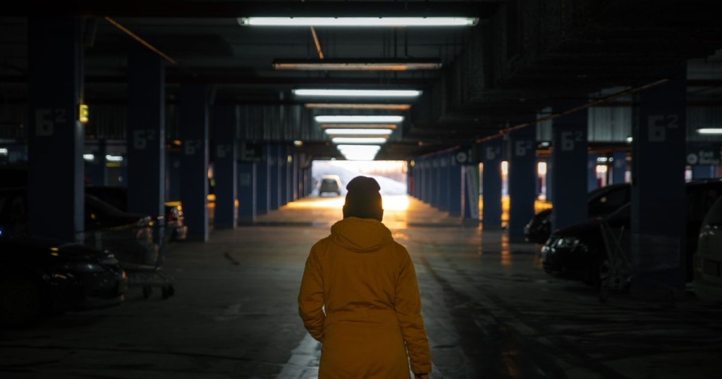 A view from behind a woman walking in a dark hospital parking garage