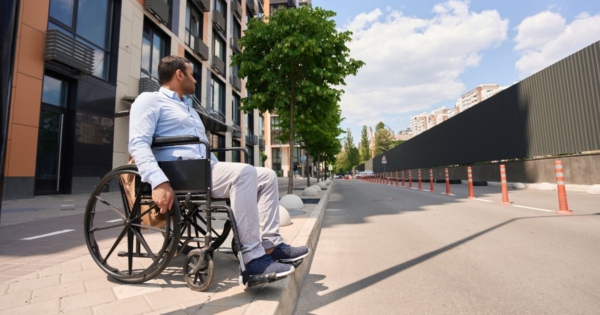 a man in a wheelchair is stranded on a sidewalk without an accessible curb cut