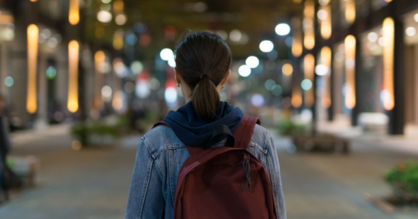young woman with a backpack walking away in the dark