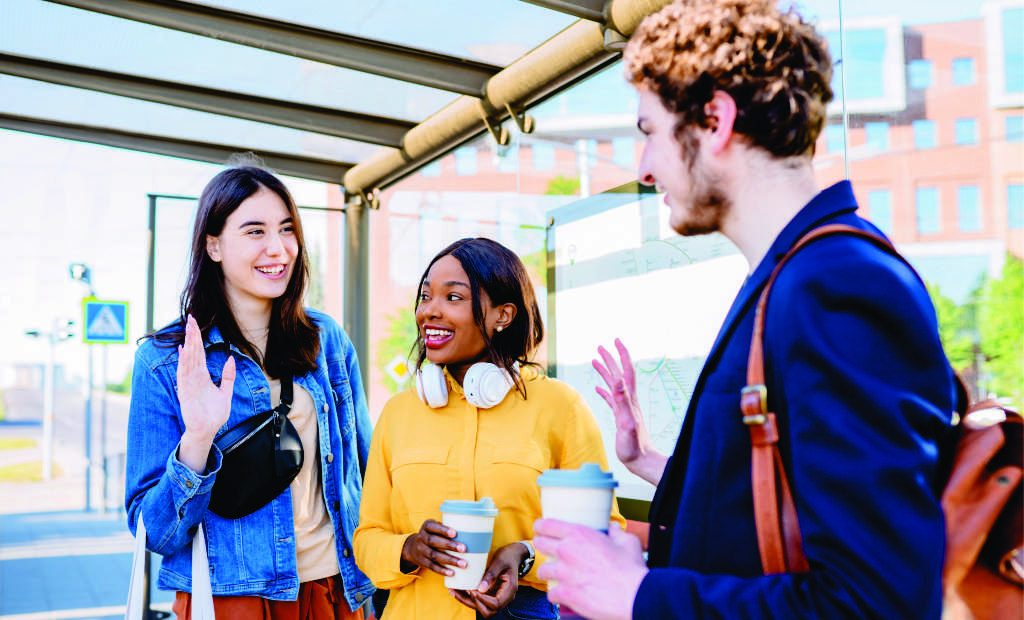 Group of three students at a college campus transit bus stop