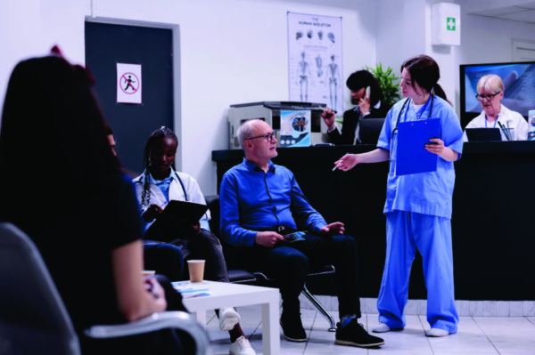 Healthcare office waiting room with a nurse speaking to an older man